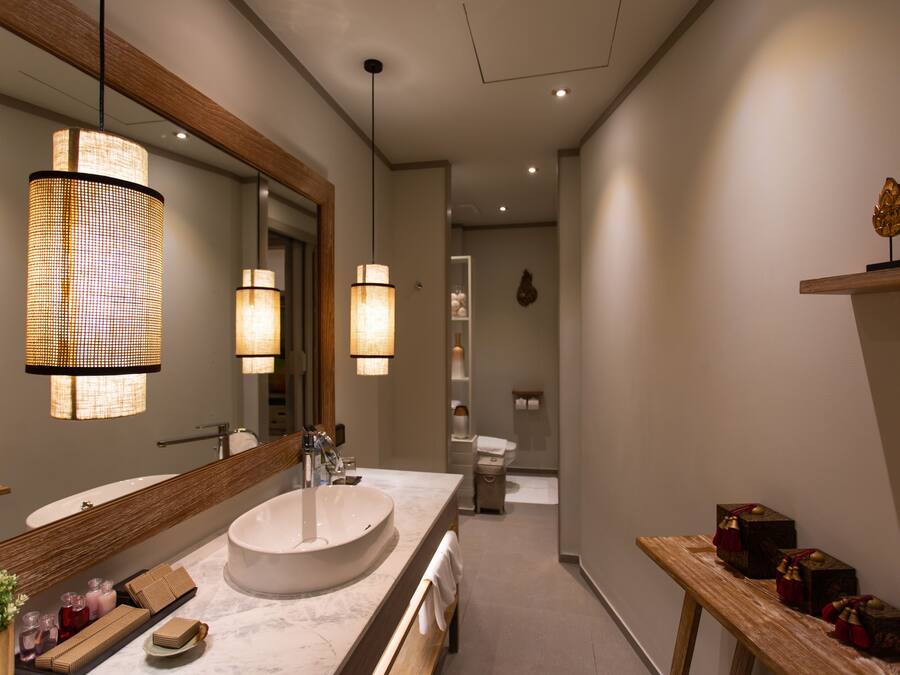 A modern bathroom with a large mirror, a round sink, and two pendant lights.