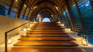 Una escalera de madera con escalones y faroles de cristal, que conduce a un techo alto con vigas de madera.