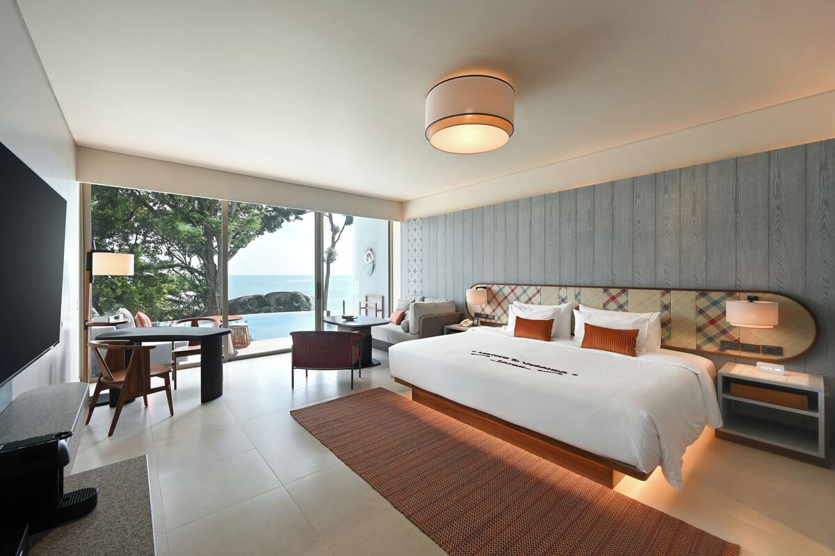 Une chambre d’hôtel moderne avec un grand lit, un bureau et une vue sur l’océan.