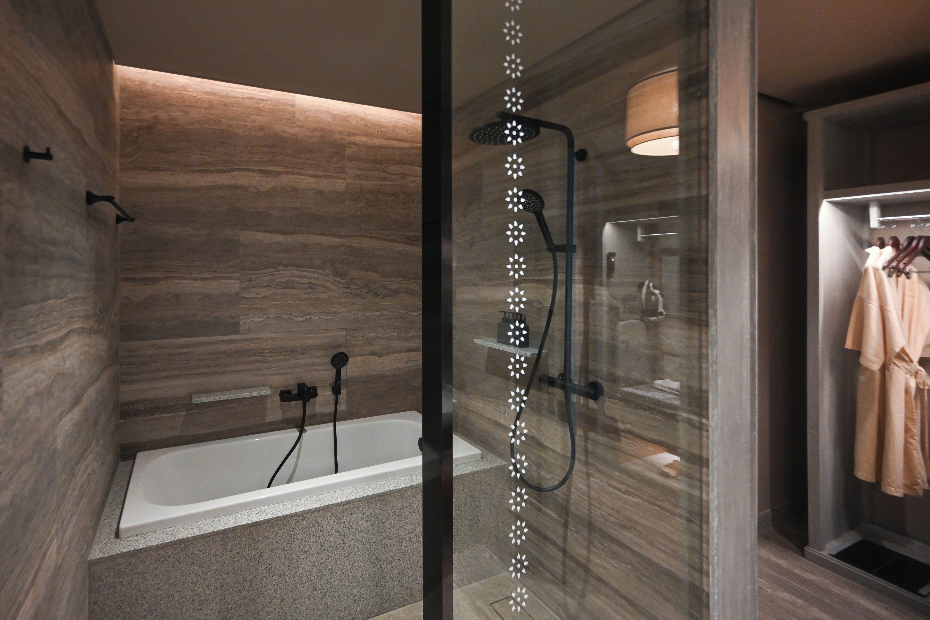 Une salle de bain moderne avec une baignoire sur pieds, une douche à l’italienne et un porte-serviettes avec des peignoirs.