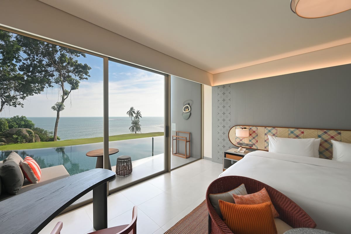 Une chambre d’hôtel moderne dotée d’une grande fenêtre en verre, d’un lit, d’un bureau et d’une chaise.