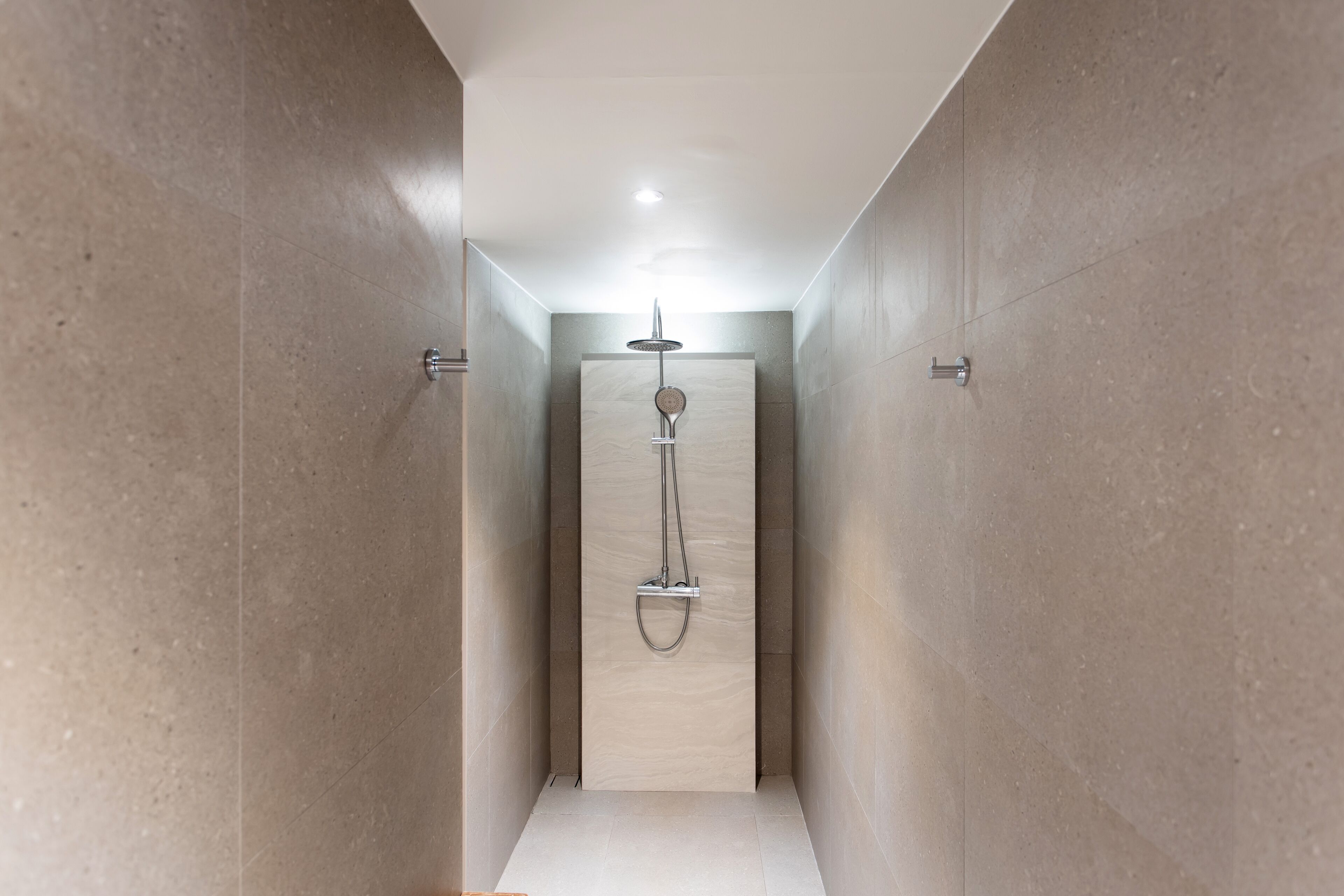 A modern bathroom with a shower, tiled walls, and a ceiling light.