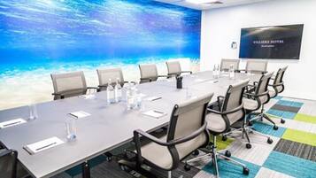 A conference room with a large table, chairs, and a water-themed wall mural.