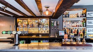 A bar with multiple taps, shelves of liquor bottles, and a wooden ceiling. - Villiers Hotel (Buckingham)