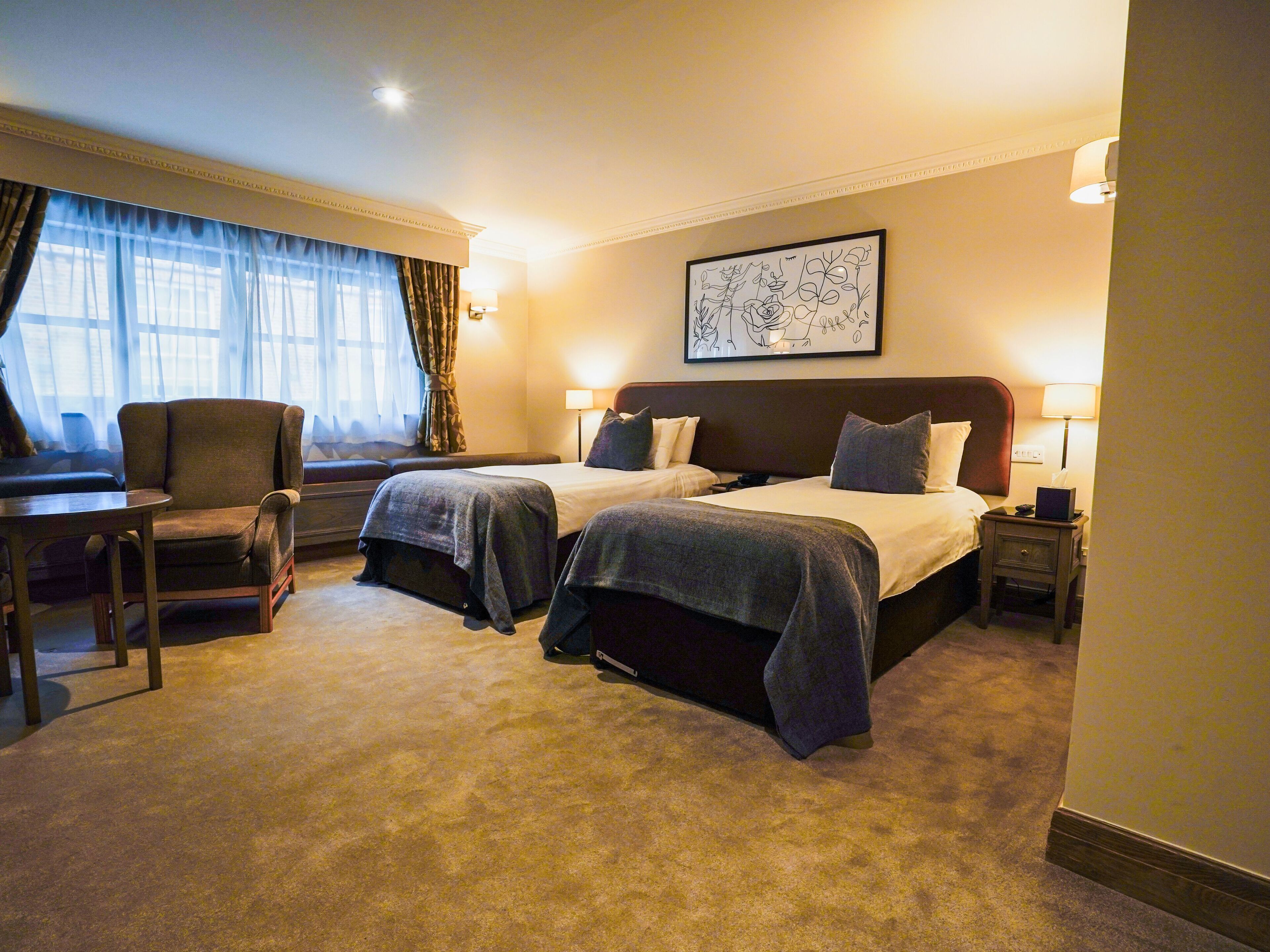 A hotel room with two beds, a desk, and a chair.