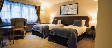A hotel room with two beds, a desk, and a chair.
