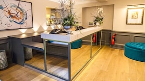 A reception area with a modern counter, a telephone, and decorative plants. - Villiers Hotel (Buckingham)