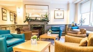 A hotel lobby with a fireplace, comfortable seating, and framed artwork on the walls. - Villiers Hotel (Buckingham)