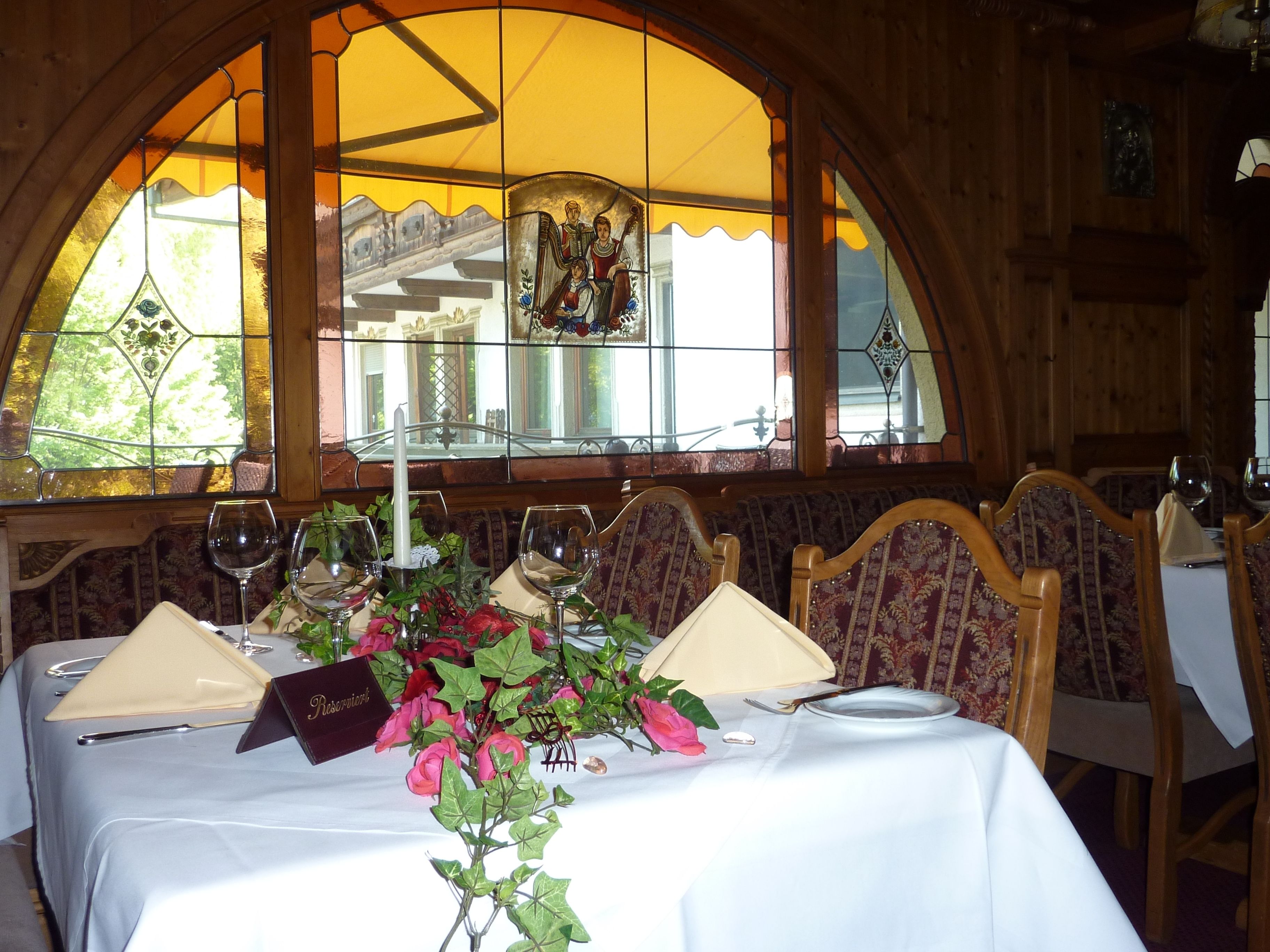 Une table à manger dressée avec des verres à vin, une bougie et un présentoir à menus.