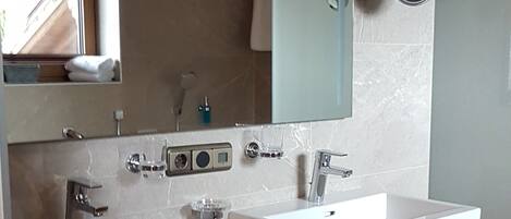 A modern bathroom with two sinks, a large mirror, and wooden storage drawers.