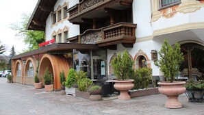 A restaurant with outdoor seating, a wooden facade, and decorative plants. - Hotel Tyrolis (Zirl)