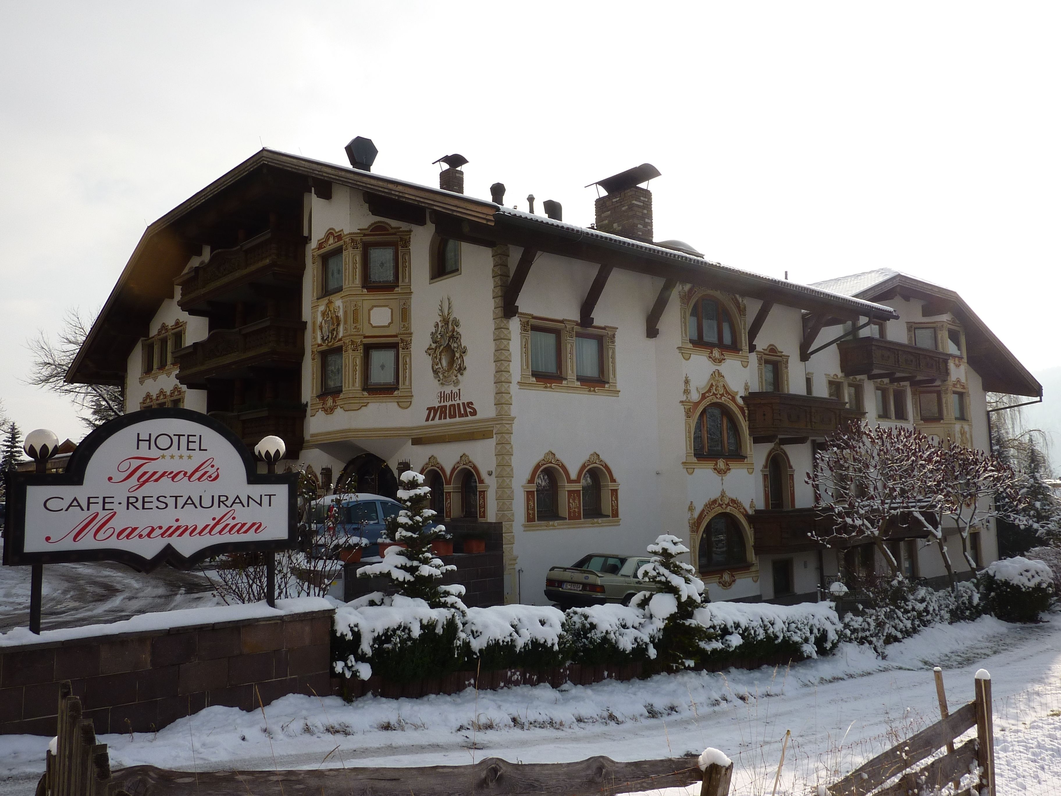Ein Hotel mit einem Schild, auf dem 'Hotel Tyrolis Café-Restaurant Maximilian' steht.