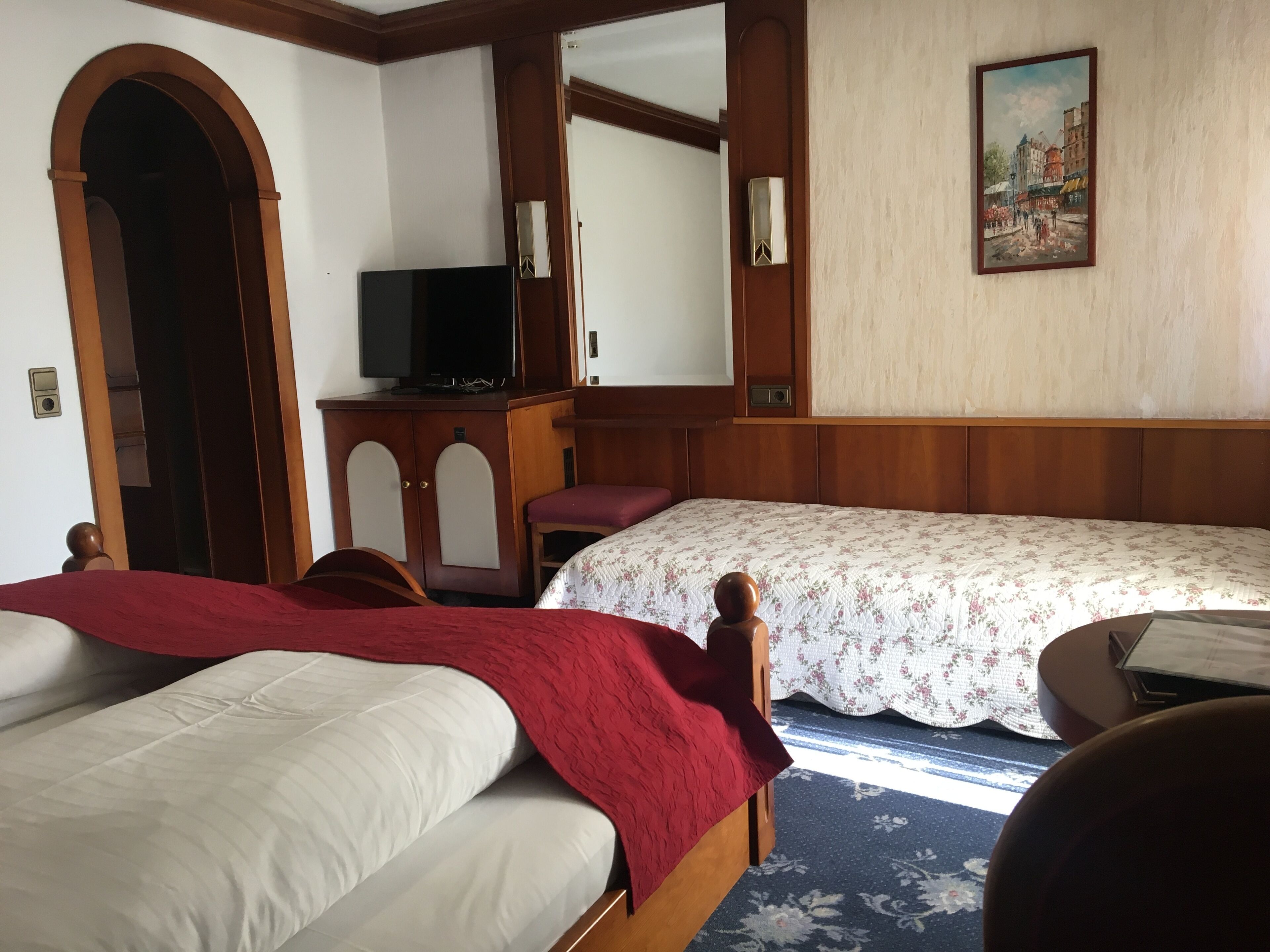 Une chambre d’hôtel avec deux lits, une télévision, un bureau et un tableau au mur.