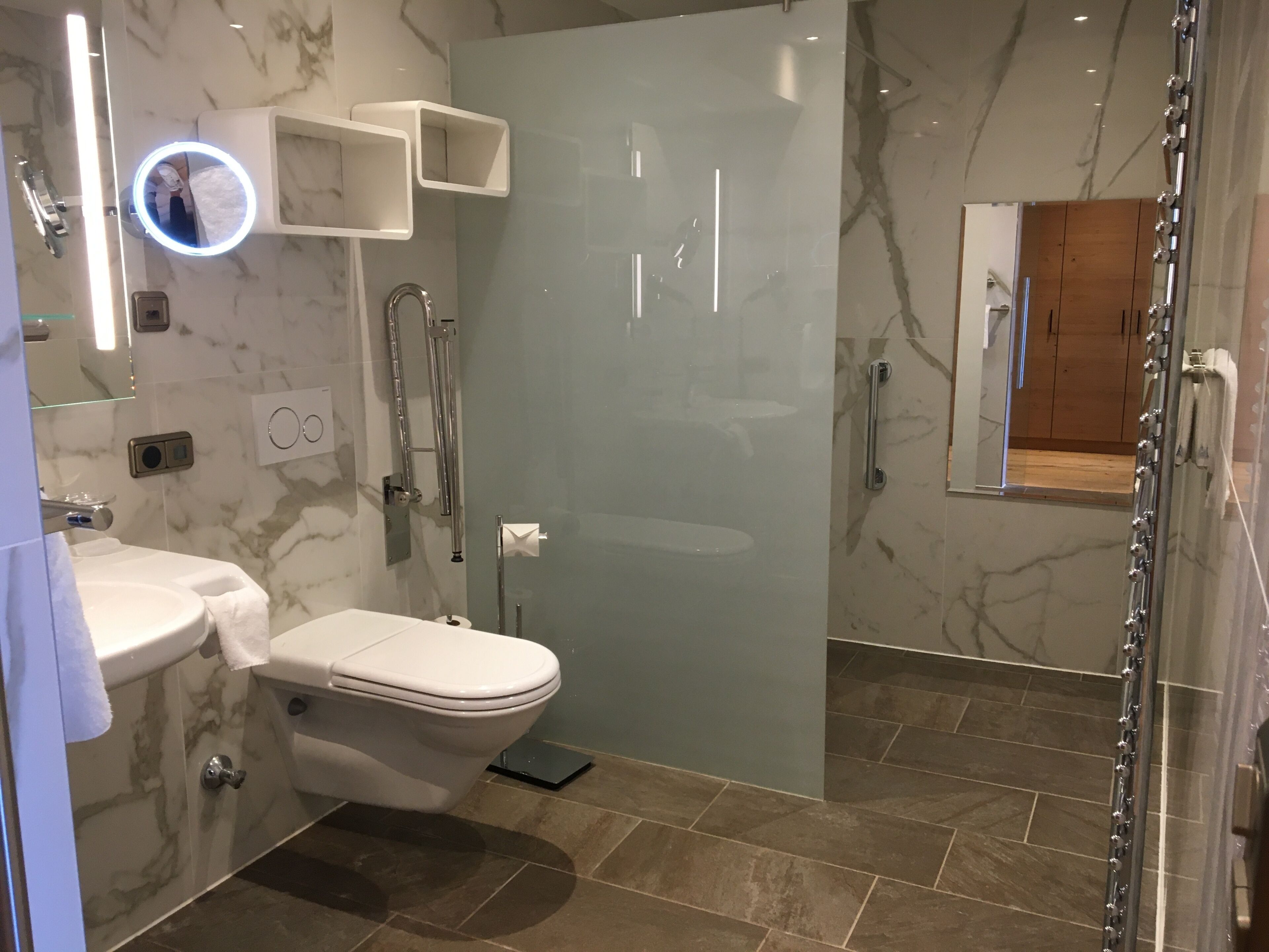 A modern bathroom with a toilet, sink, and glass shower enclosure.