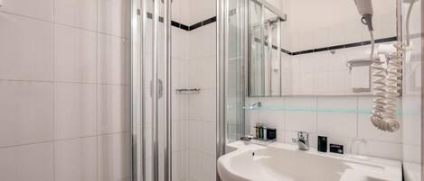 Un baño moderno con cabina de ducha de vidrio, un lavabo blanco y un espejo encima.