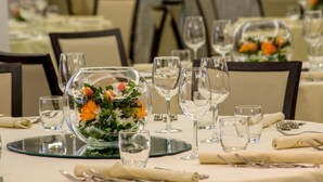Una mesa de comedor dispuesta con cristalería transparente, platos y una lámpara de cristal decorativa en el centro.