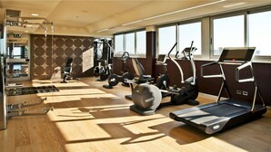 Un gimnasio moderno con diverso equipamiento de ejercicio, ventanas amplias y suelo de madera.