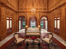 Una habitación lujosa con una cama grande, muebles de madera elaborados y detalles arquitectónicos intrincados.