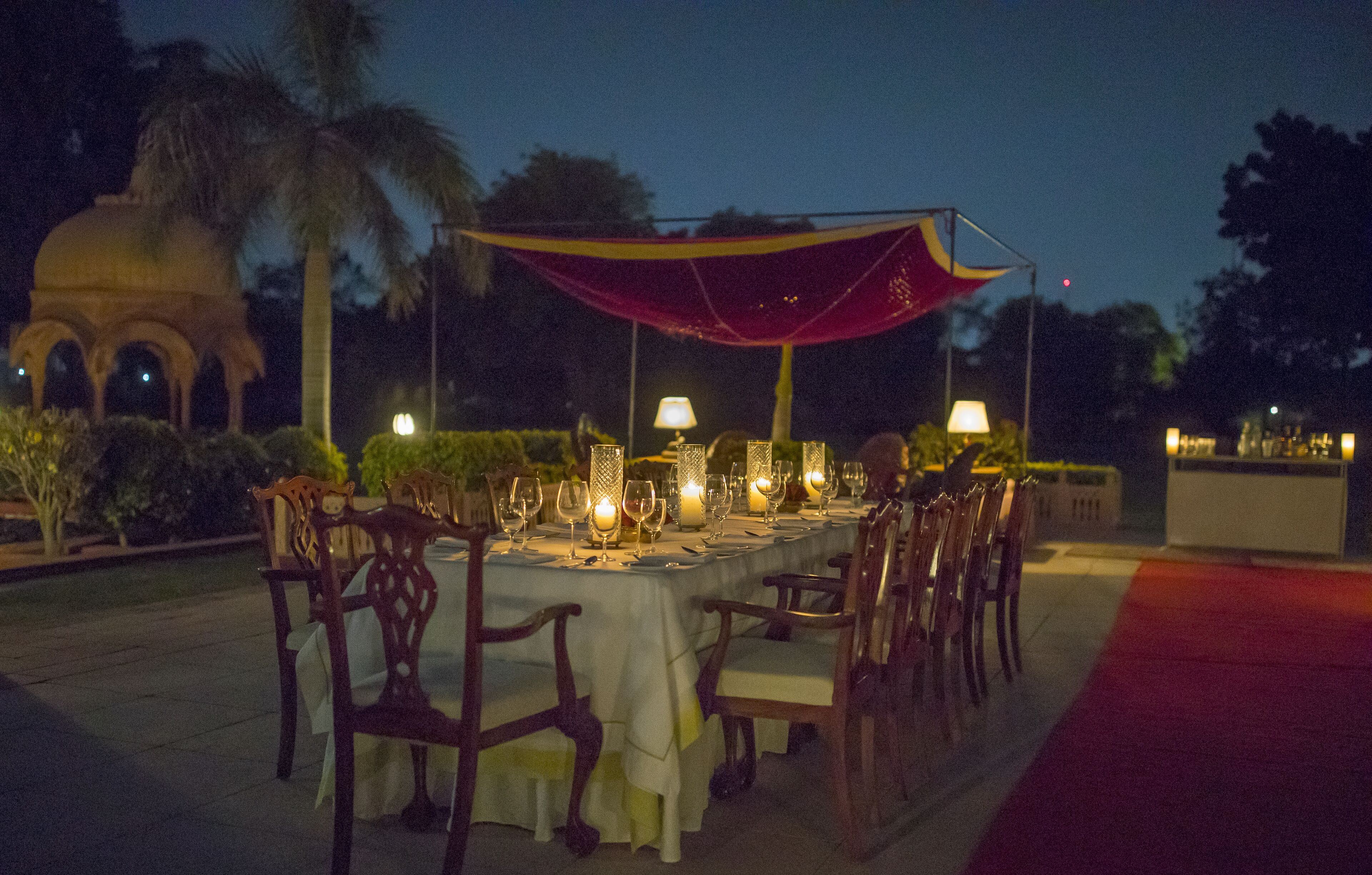 Un área de comedor al aire libre con una mesa dispuesta para seis personas, rodeada de sillas y cubierta por una marquesina.