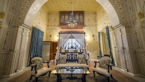 A luxurious room with ornate ceiling, a glass table, and four upholstered chairs. - The Laxmi Niwas Palace (Bikaner)