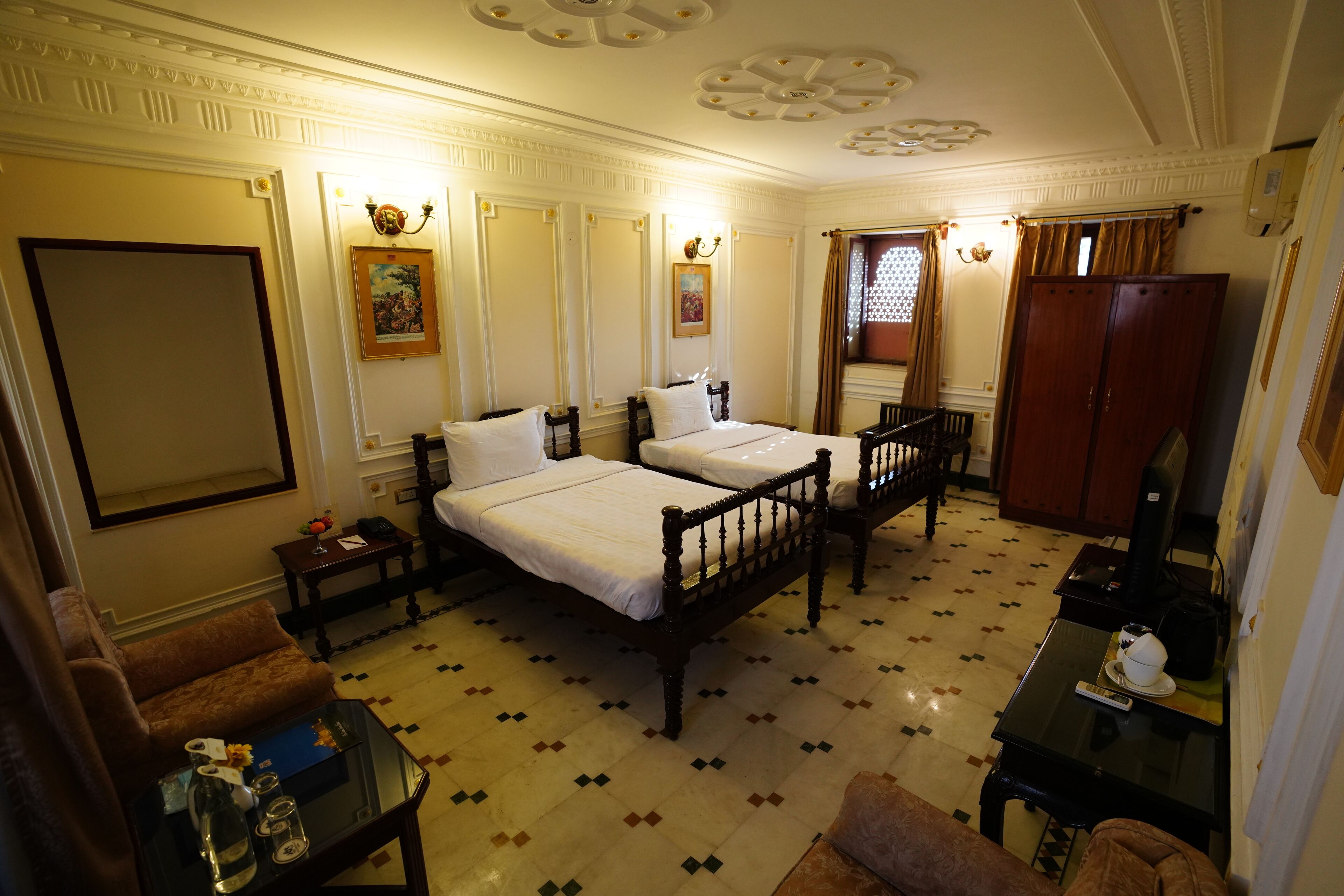 Une chambre d’hôtel avec deux lits, un canapé, une petite table et une armoire.