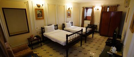 A hotel room with two beds, a sofa, a small table, and a wardrobe.