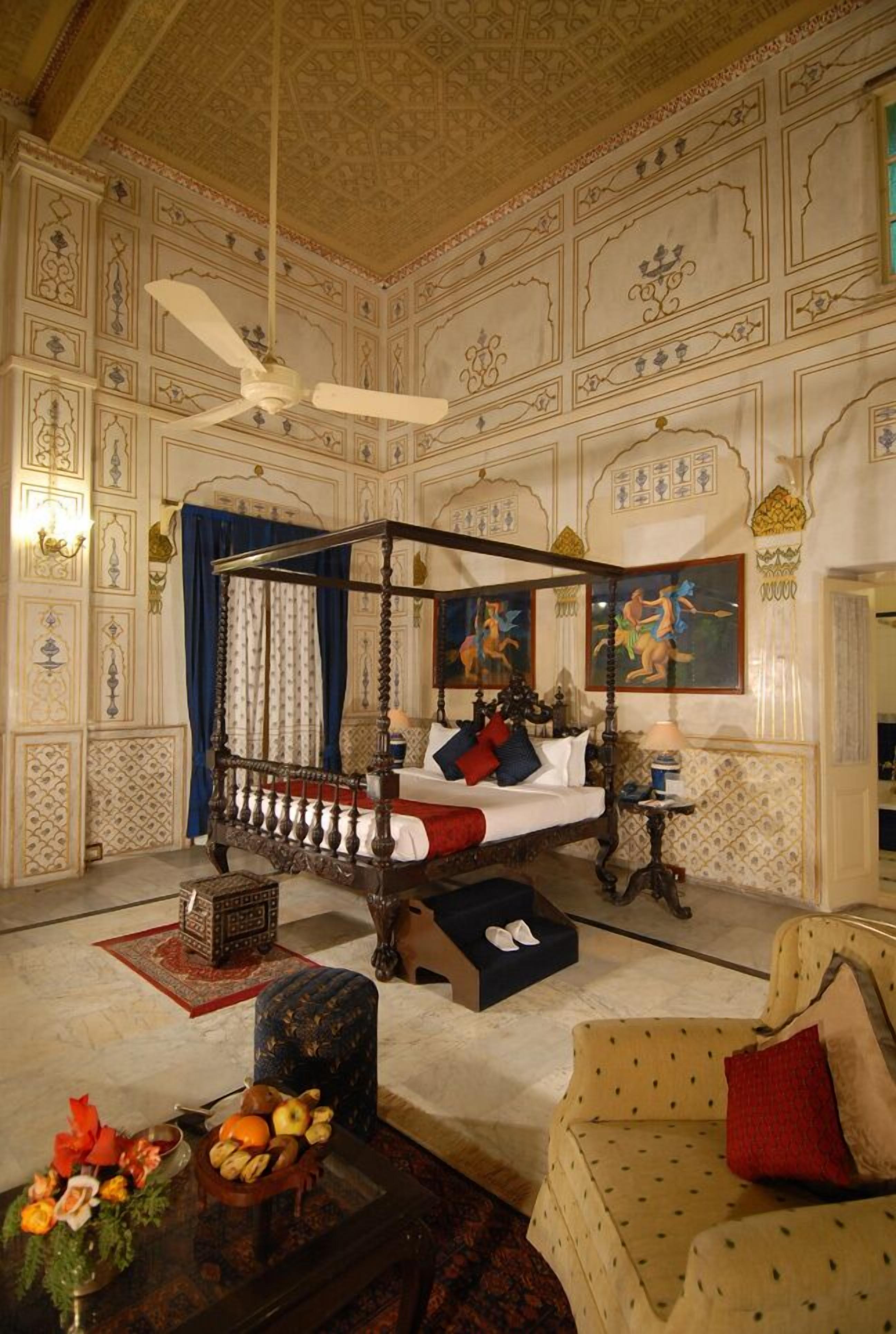 Una habitación tradicional con cama con dosel, ventilador de techo y decoraciones de pared ornamentales.