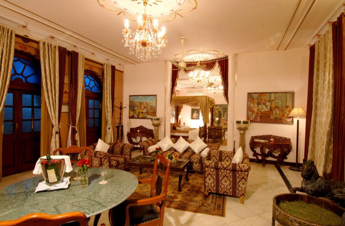 Una habitación tradicional con comedor, sofás, una araña y obras de arte en las paredes.