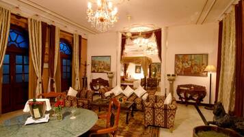 Una habitación tradicional con comedor, sofás, una araña y obras de arte en las paredes.