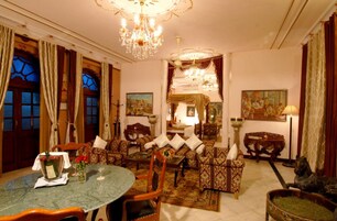 Una habitación tradicional con comedor, sofás, una araña y obras de arte en las paredes.