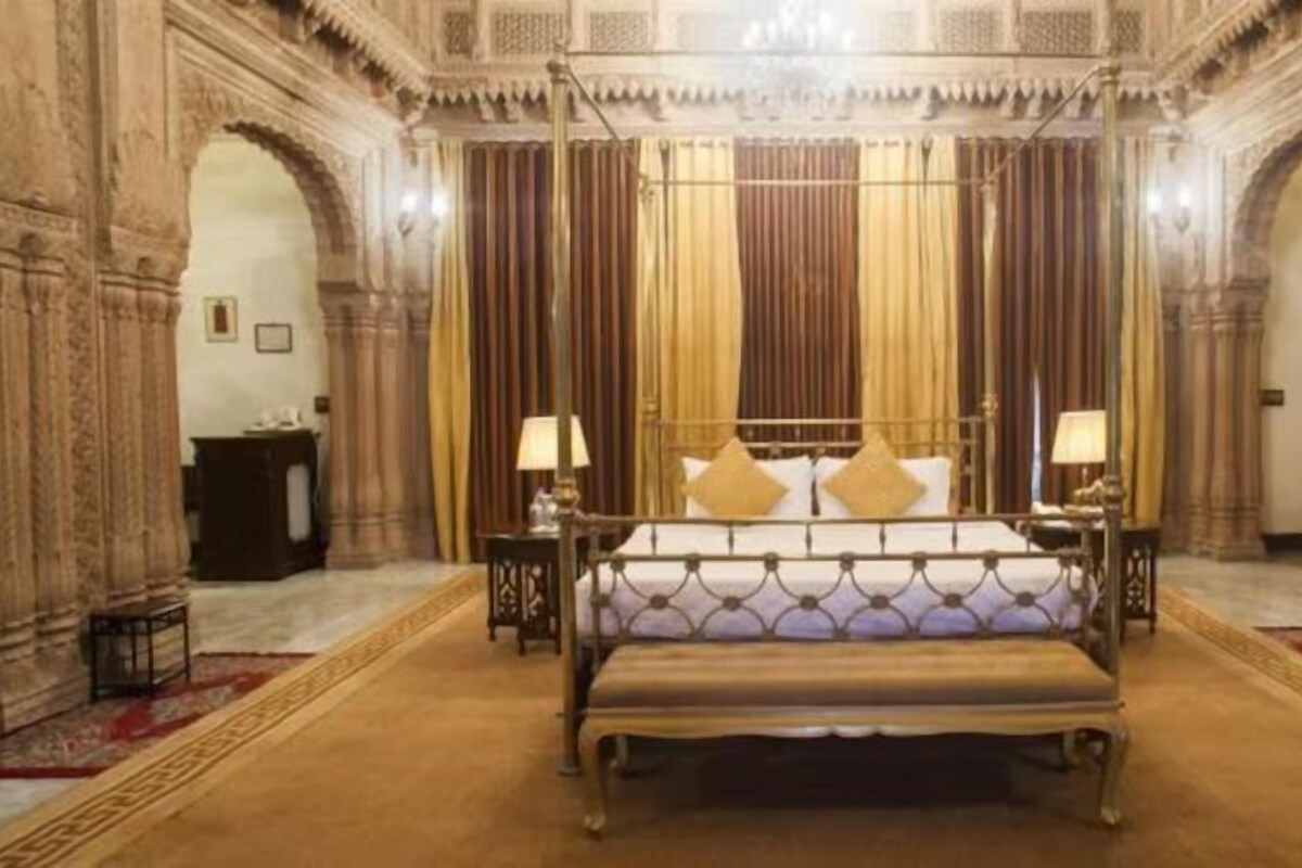 Een luxueuze slaapkamer met een groot bed, sierlijke gordijnen en gedetailleerde wanddecoraties.