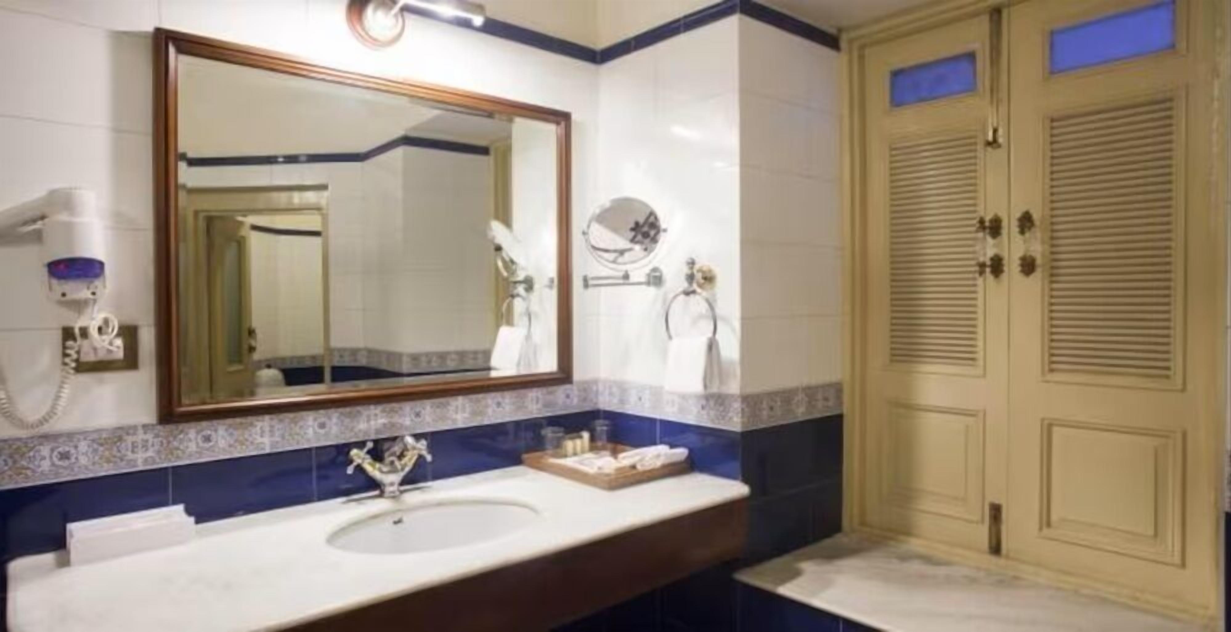 Une salle de bain avec un lavabo, un miroir, un porte-serviettes et une porte sur laquelle est accrochée une serviette.