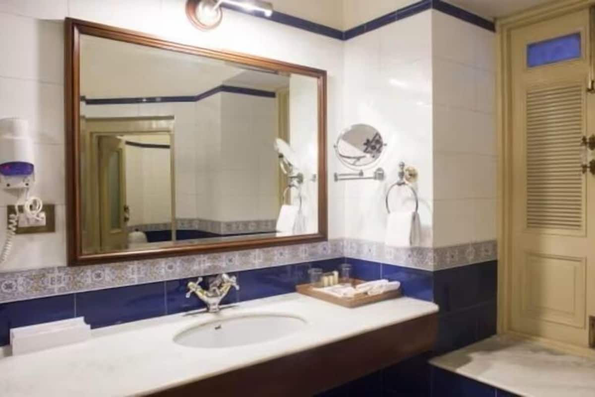 Une salle de bain avec un lavabo, un miroir, un porte-serviettes et une porte sur laquelle est accrochée une serviette.