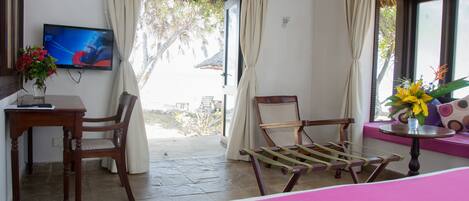 A hotel room with a bed, a desk with a chair, a TV, and a window with curtains.