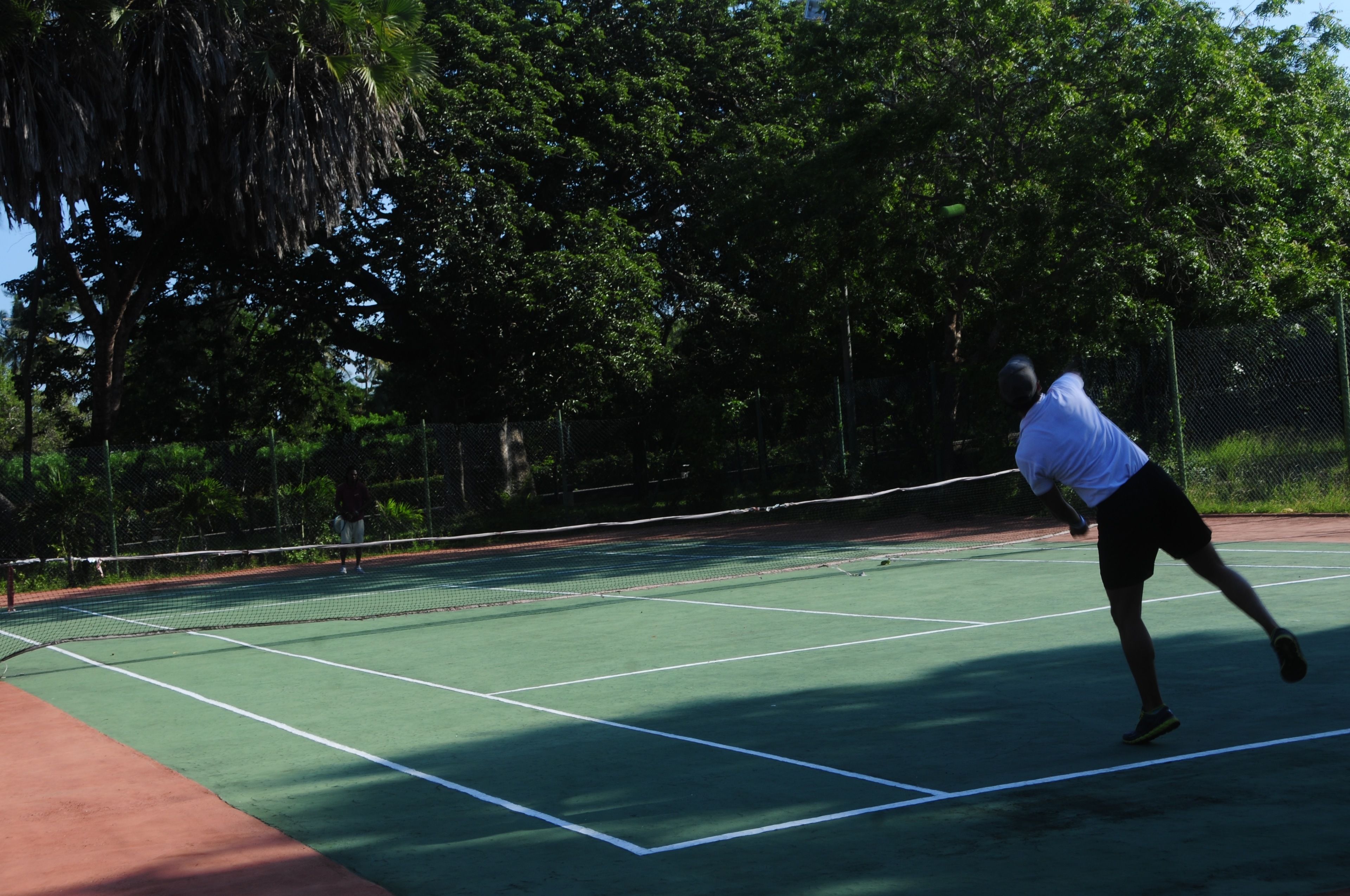 Una cancha de tenis con una red, rodeada de árboles.