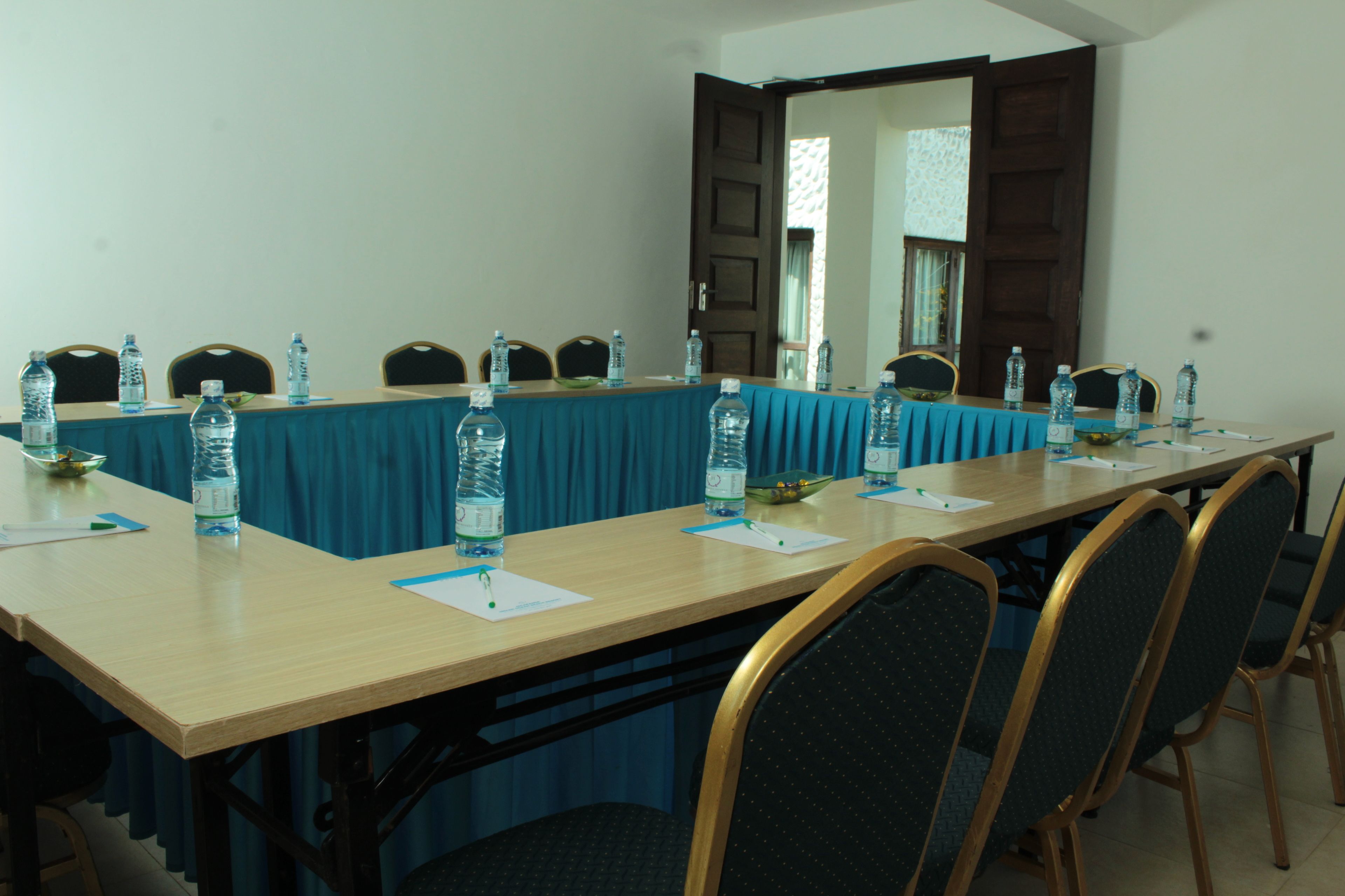 A conference room with a long table, chairs, water bottles, and papers.