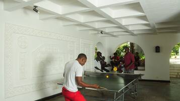A man playing table tennis in a room with white walls and geometric patterns.