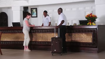 A reception desk with a wooden panel design, a framed picture on the wall, and a vase with flowers.