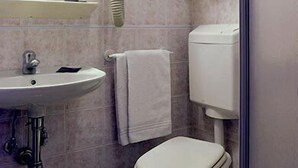 Un baño con lavamanos, inodoro, espejo, secador de manos y toallero.
