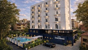 A modern hotel with a pool, surrounded by greenery and other buildings. - Hotel Biancamano (Rimini)