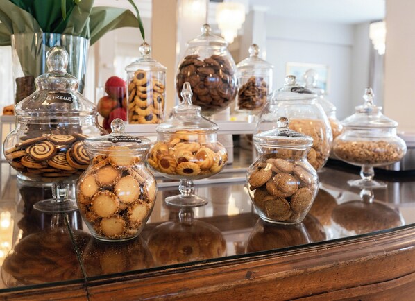 A variety of cookies and pastries displayed in glass jars on a wooden counter.