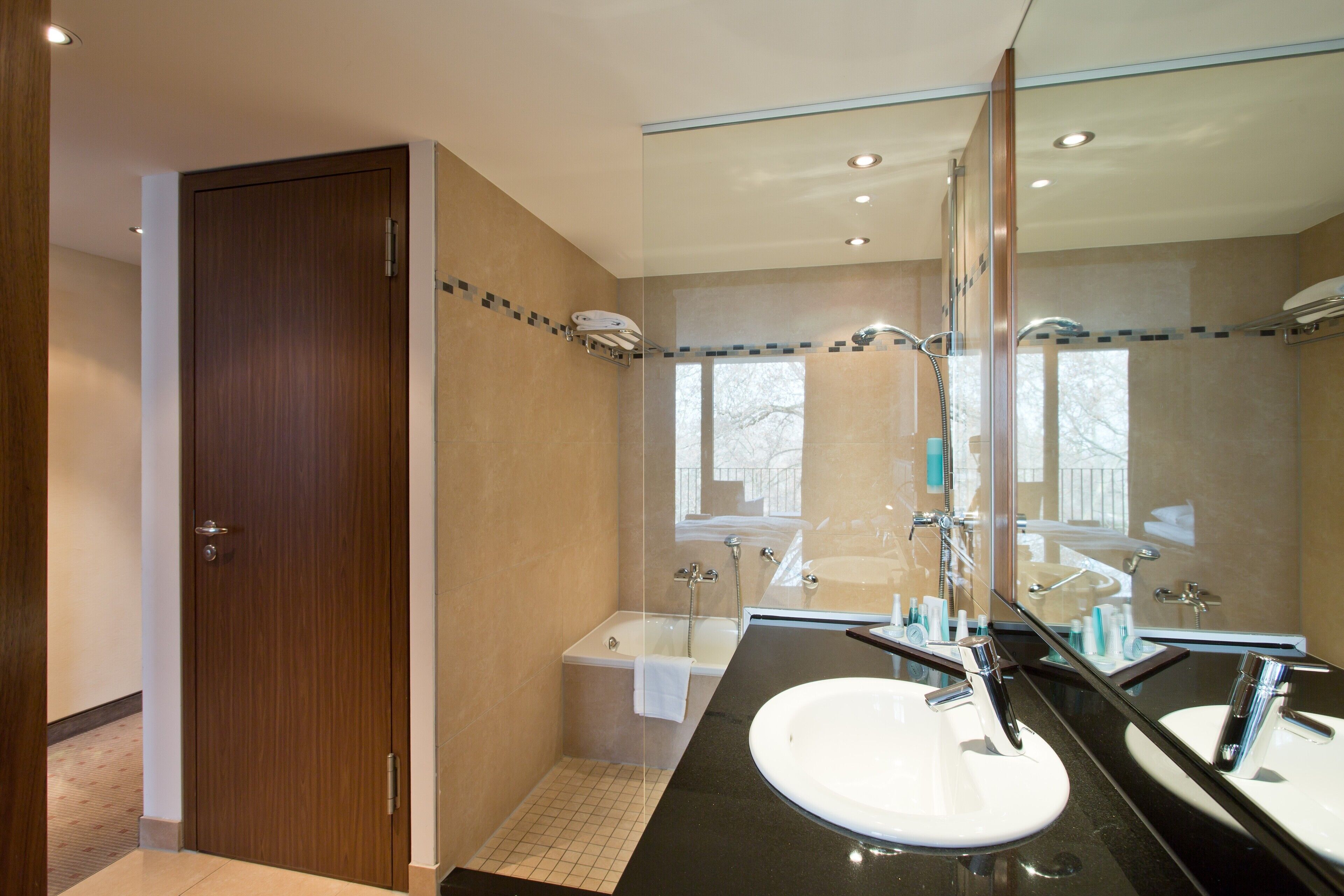 Un baño moderno con un espejo grande, una bañera y un lavamanos.