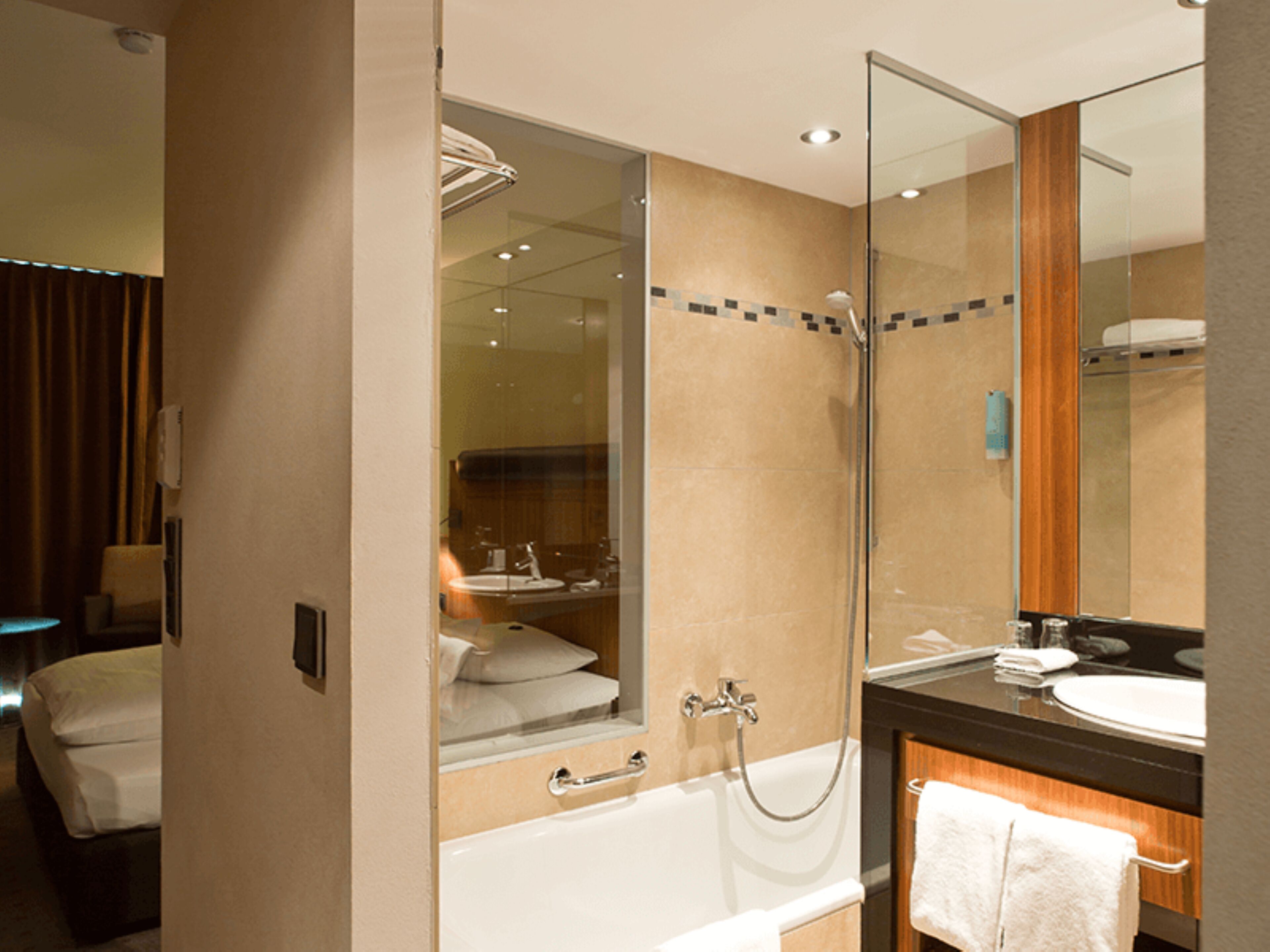 Un baño moderno con cabina de ducha de vidrio, bañera, lavabo y espejo.