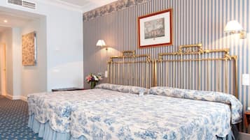A hotel room with a large bed, a headboard with a decorative design, a wall-mounted picture, and a bedside lamp.