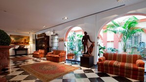 A lobby with a checkered floor, a statue, and a large plant. - Hotel Doña Maria (Seville)