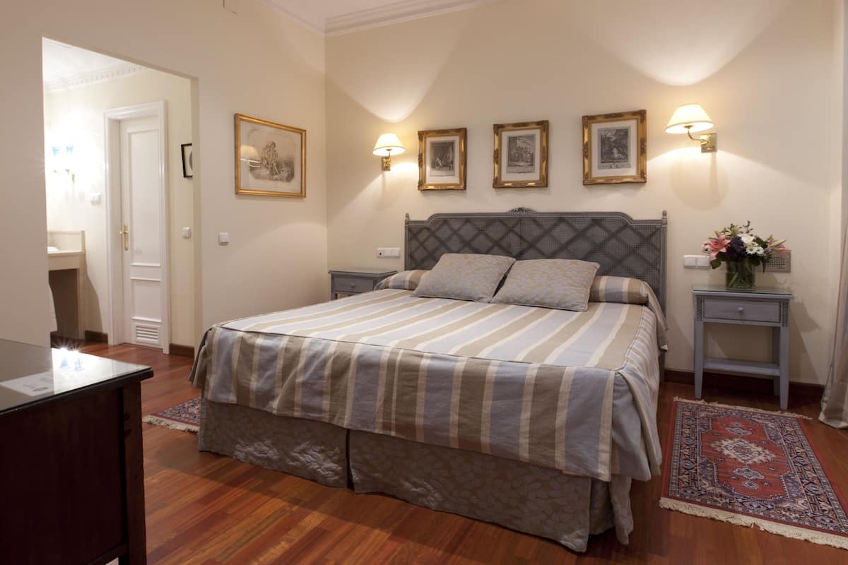 A neatly arranged bedroom with a bed, bedside tables, and a desk.