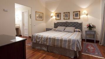 A neatly arranged bedroom with a bed, bedside tables, and a desk.