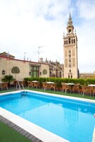 A swimming pool with lounge chairs and a view of a historic tower.
