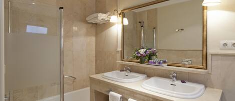 A modern bathroom with a glass-enclosed shower, two sinks, a large mirror, and a vanity with a towel rack.