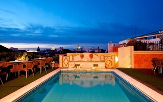 Piscina al aire libre con vistas a un paisaje urbano al anochecer.